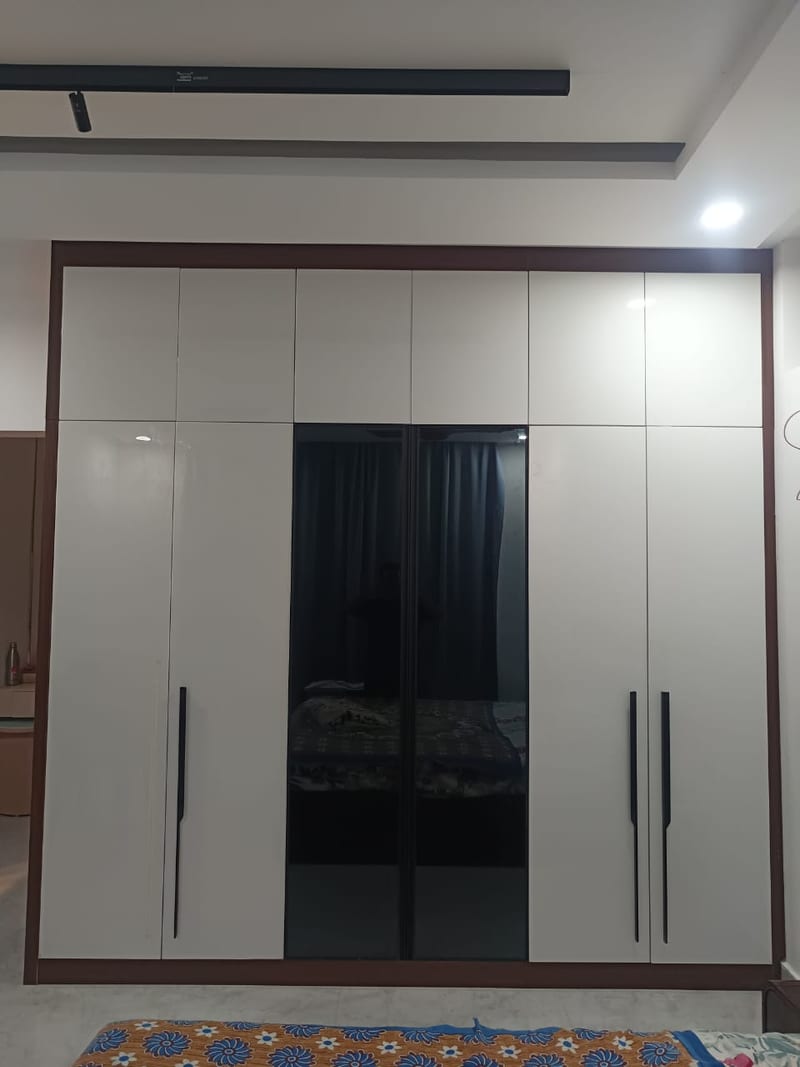 A white hinged wardrobe with glass panels in the centre doors